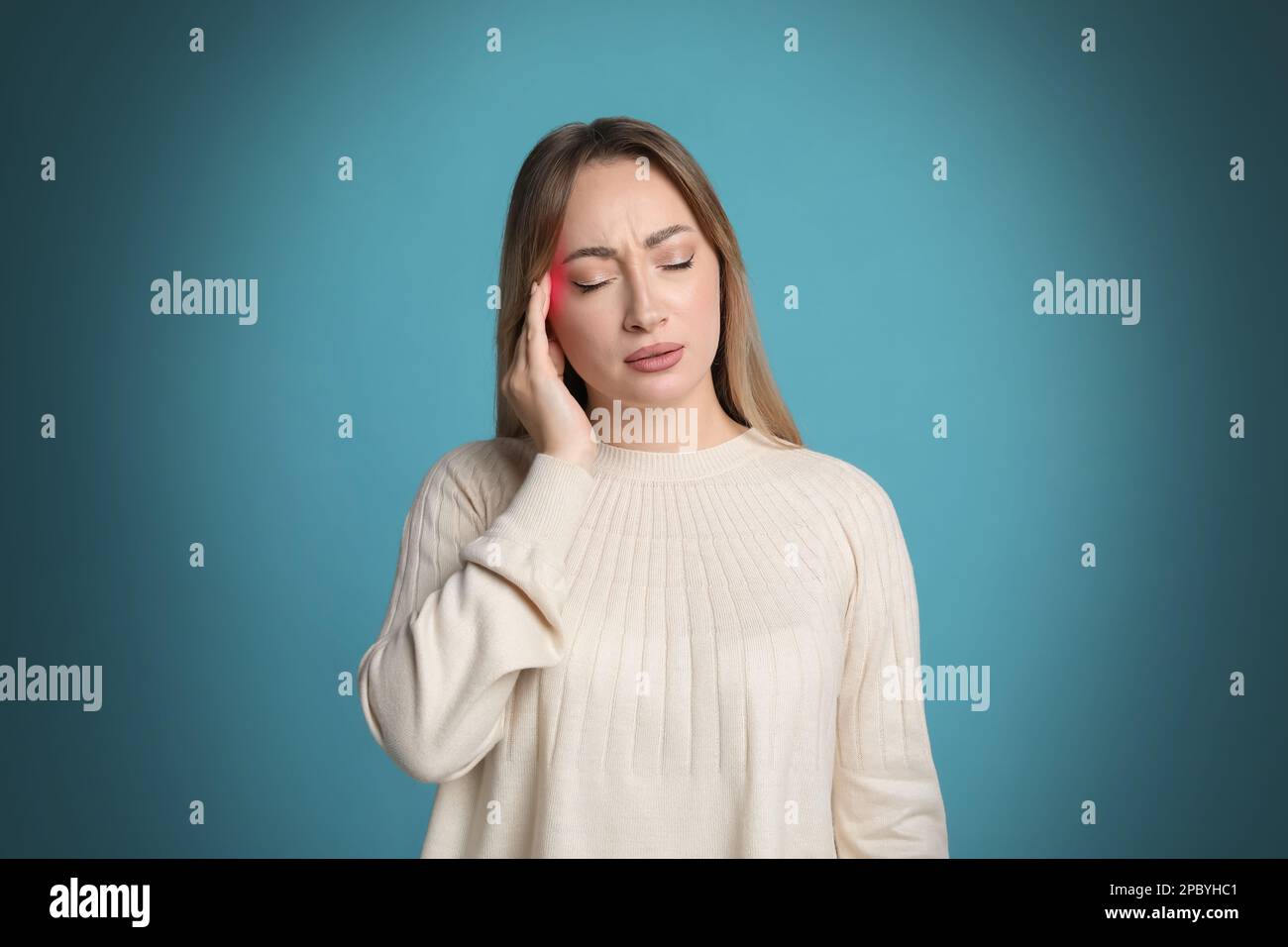 Giovane donna che ha mal di testa su sfondo azzurro Foto Stock