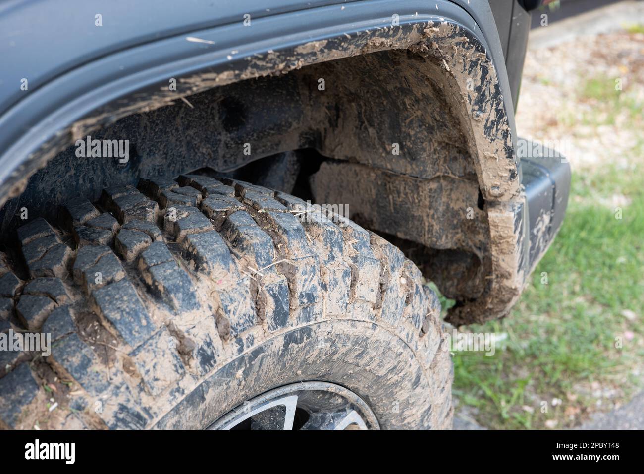 Fango secco sui pneumatici di fango fuoristrada del SUV. Primo piano, vista dall'angolo basso, nessuna persona. Foto Stock