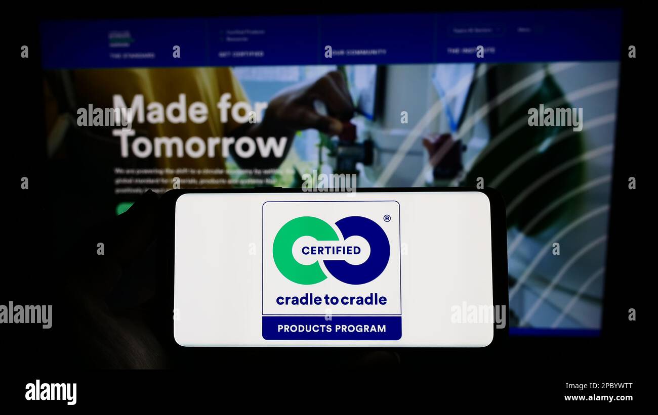 Persona che tiene lo smartphone con il logo dell'etichetta ambientale supporto per supporto certificato sullo schermo di fronte al sito Web. Messa a fuoco sul display del telefono. Foto Stock