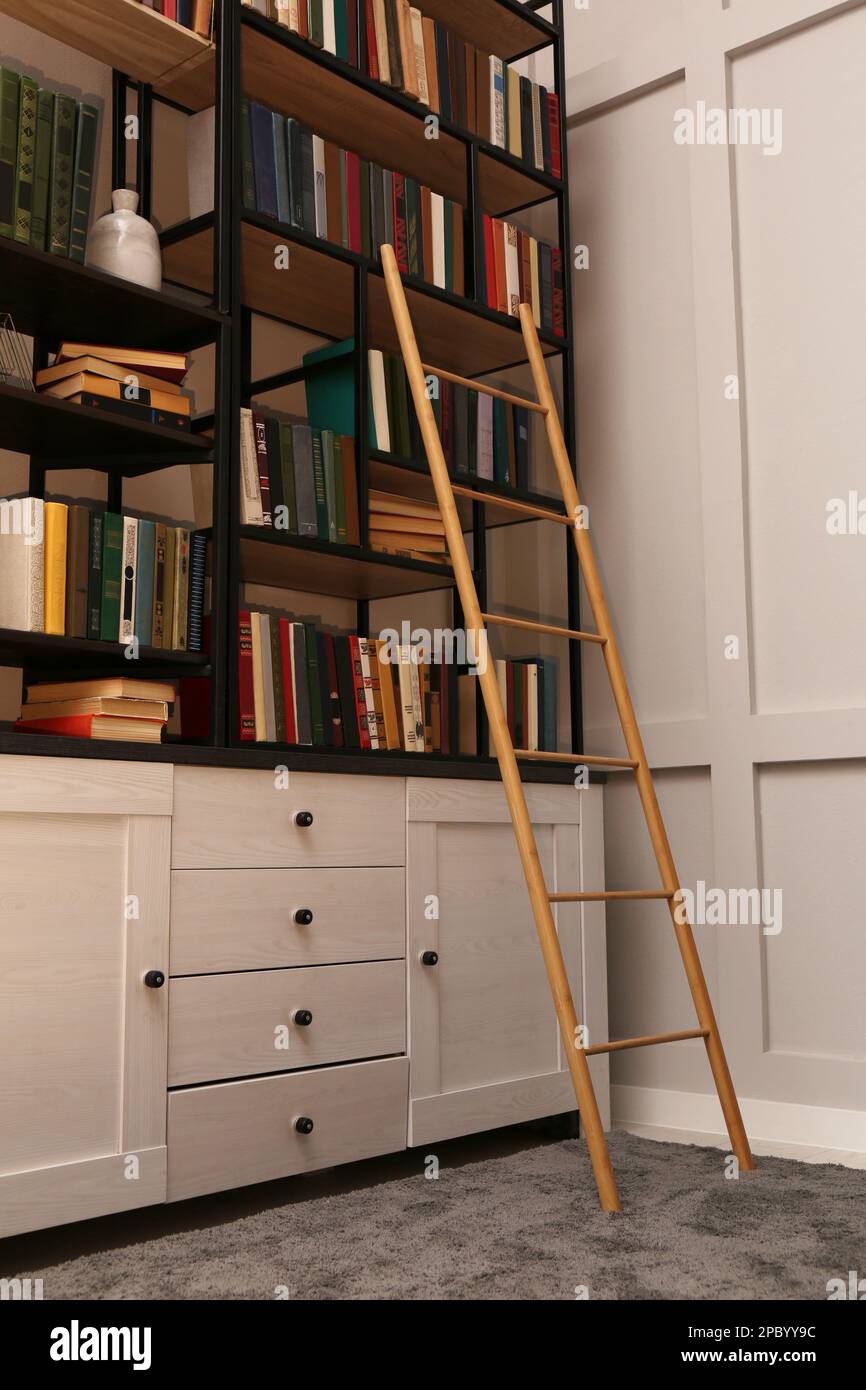 Interno biblioteca con scala in legno e raccolta di libri su scaffali Foto Stock