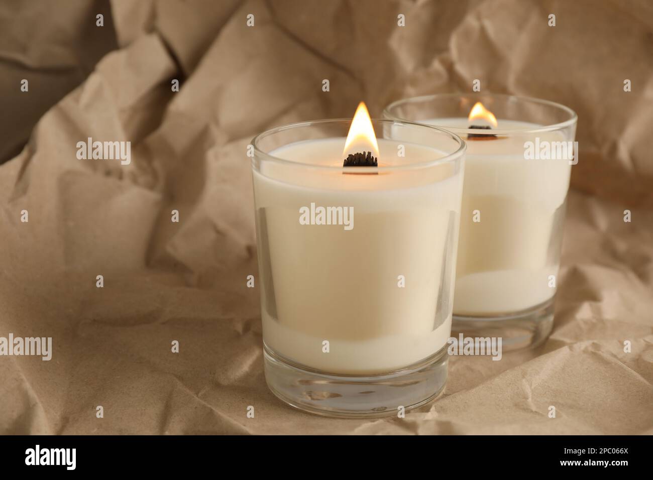 Bruciare le candele di soia con i pulcini di legno su carta grattugiata del kraft Foto Stock