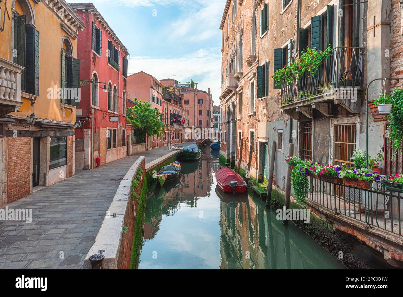 Venezia, Italia. Vista sulla strada medievale veneziana con antichi edifici colorati e ponte sul canale d'acqua con barche a Venezia, Veneto, Italia Foto Stock