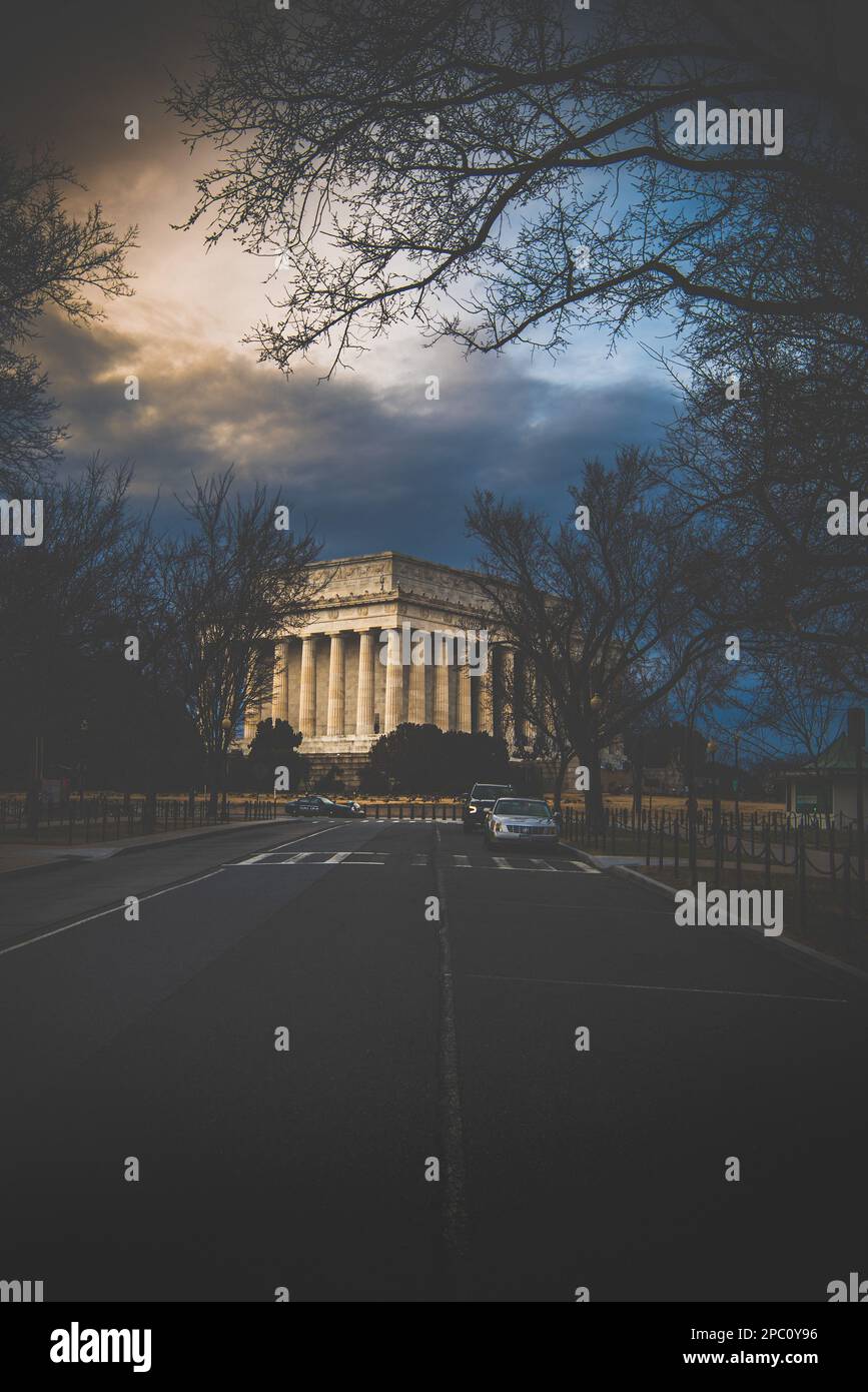 Washington DC, 9 febbraio 2023; vista del Lincoln Memorial al tramonto con cielo nuvoloso giù per una strada laterale con automobili e alberi che sovrastano in inverno Foto Stock