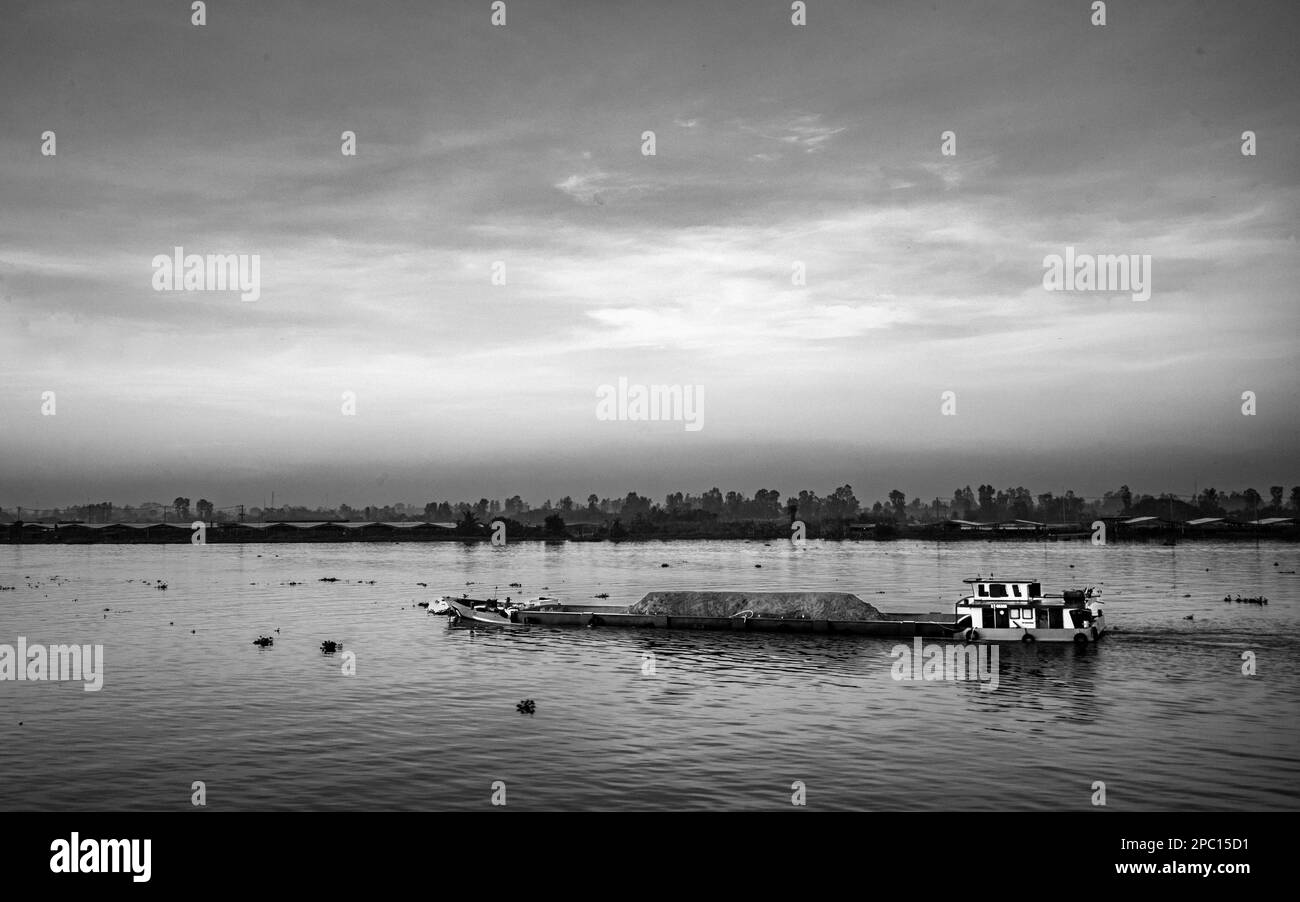Una chiatta carica di sabbia dragata dal letto del fiume Mekong fa il suo senso attraverso il delta del Mekong vicino a Long Xuyen in Vietnam. Foto Stock