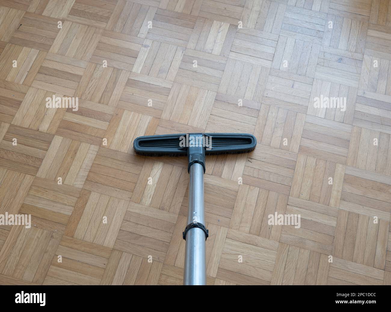 Spazzola per aspirapolvere e asta di prolunga per uso domestico su una superficie in piastrelle di legno laminate all'interno di un generico appartamento. Inquadratura ravvicinata verso il basso, senza sbirciature Foto Stock