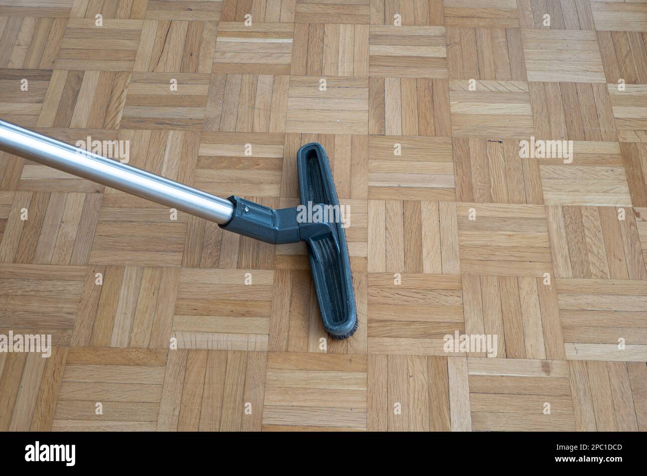 Spazzola per aspirapolvere e asta di prolunga per uso domestico su una superficie in piastrelle di legno laminate all'interno di un generico appartamento. Inquadratura ravvicinata verso il basso, senza sbirciature Foto Stock