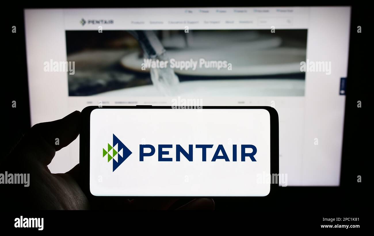 Persona che tiene il cellulare con il logo della società di trattamento delle acque Pentair plc sullo schermo di fronte al sito web aziendale. Messa a fuoco sul display del telefono. Foto Stock