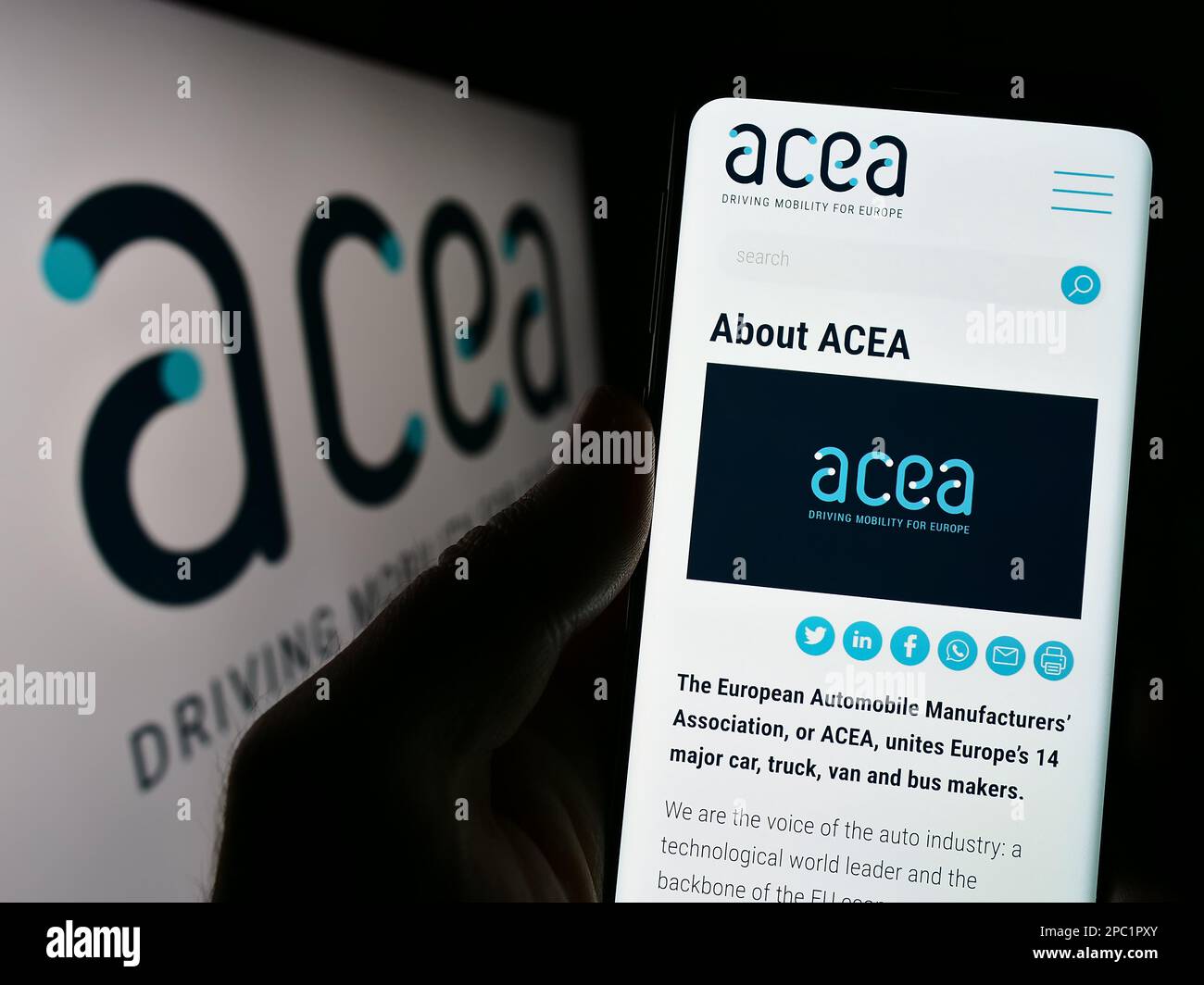 Persona che tiene il cellulare con il sito web dell'Associazione europea dei costruttori di automobili (ACEA) sullo schermo. Messa a fuoco al centro del display del telefono. Foto Stock