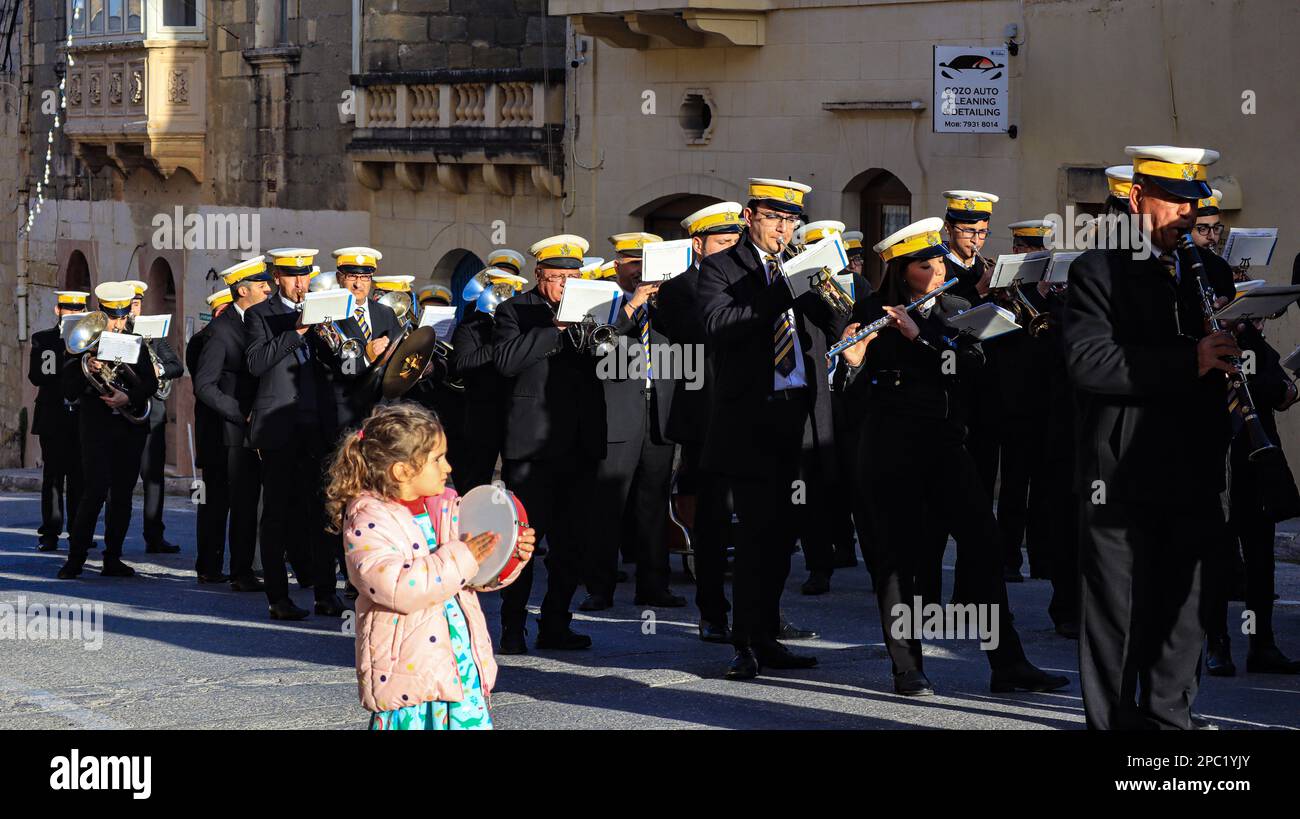 Festa di San Gregorio Magno, Kercem, Gozo. Un bambino cammina accanto a una banda di ottone con il suo tamburello. Foto Stock