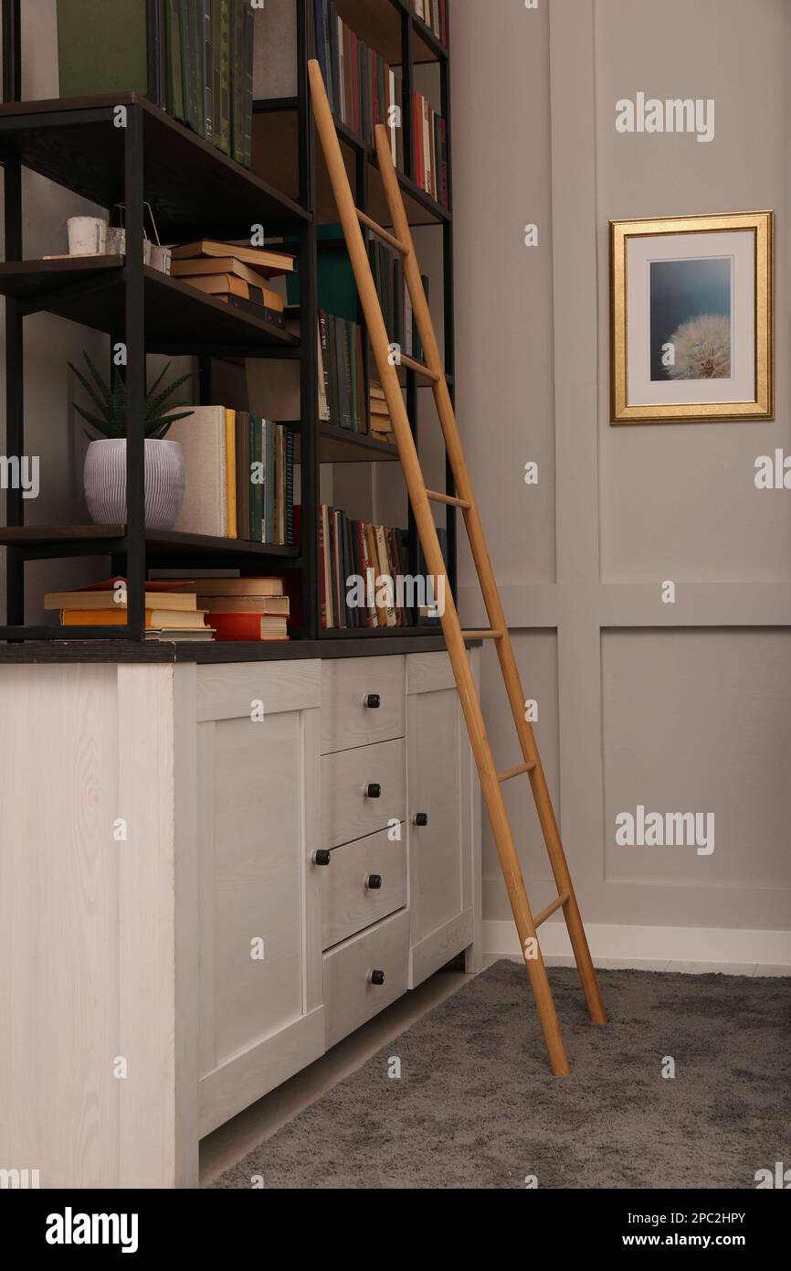 Interno biblioteca con scala in legno e raccolta di libri su scaffali Foto Stock