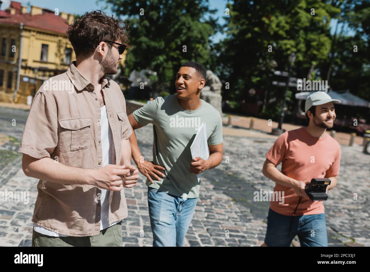 Buon turista afro-americano con mappa di viaggio che parla con la guida durante la passeggiata sulla discesa Andrews a Kiev, immagine di scorta Foto Stock