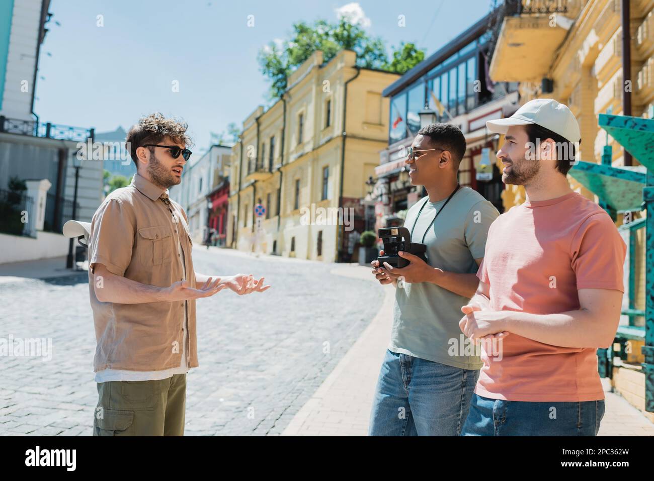 Guida parlare con gli amici interracial con fotocamera retrò su Podil a Kiev in estate, immagine stock Foto Stock