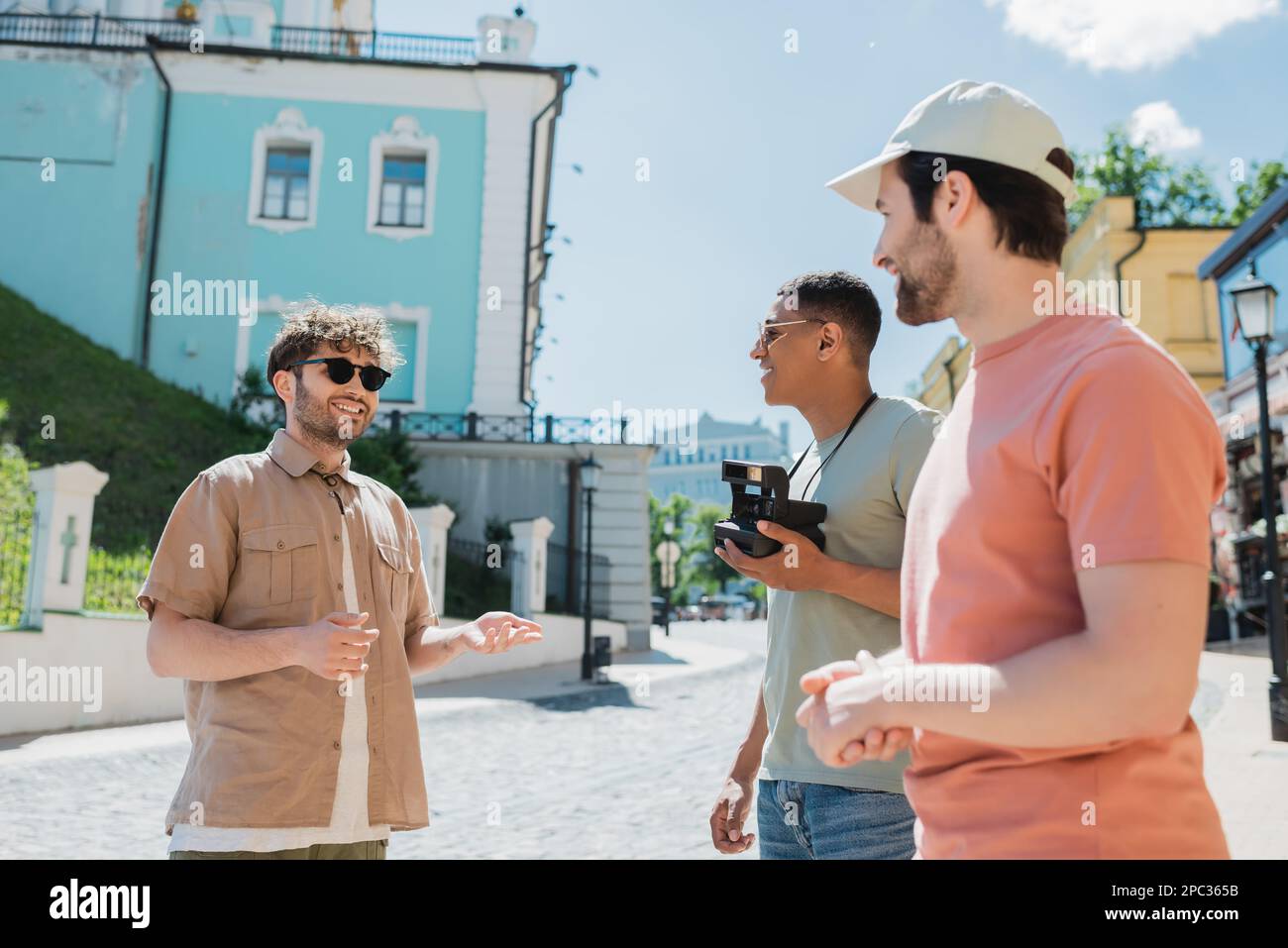 Allegra guida turistica gesturante durante l'escursione con viaggiatori multietnici sulla discesa di Andrews a Kyiv il giorno d'estate, immagine di scorta Foto Stock