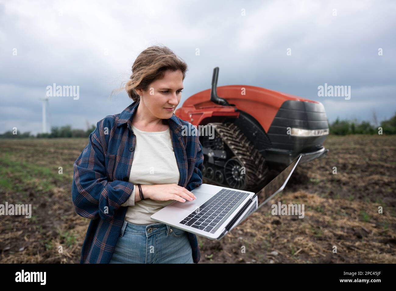 Un agricoltore con tablet digitale controlla un trattore autonomo in un'azienda agricola intelligente Foto Stock