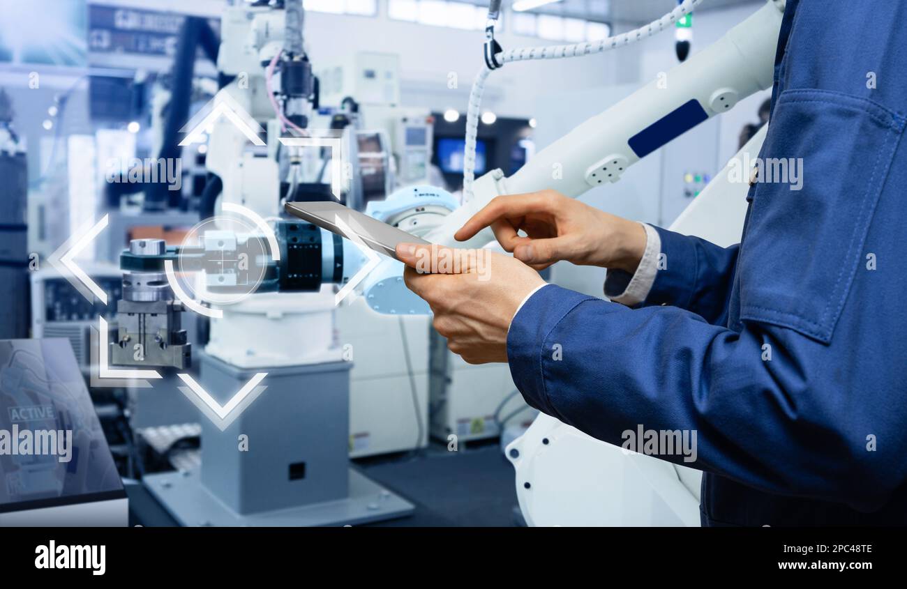 Il tecnico utilizza un tablet digitale per controllare i robot in una fabbrica intelligente. Concetto Smart Industry 4,0 Foto Stock