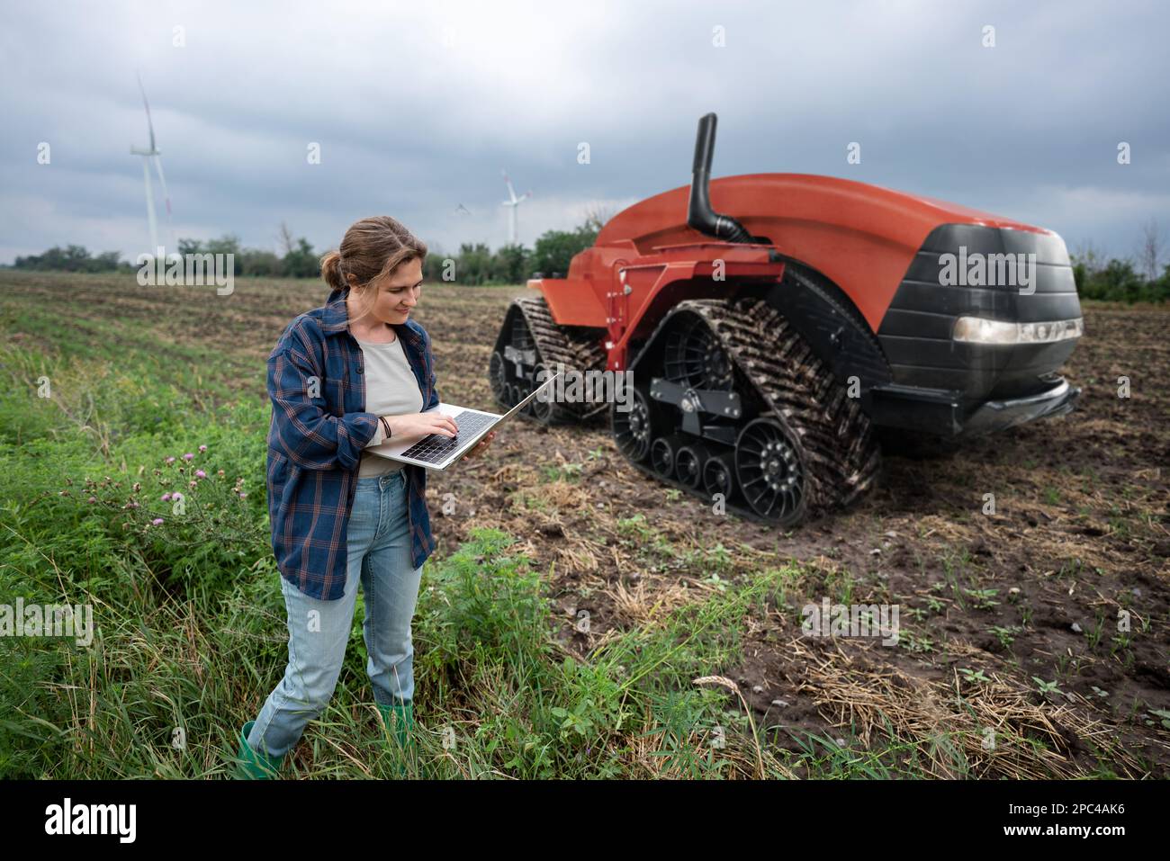 Un agricoltore con tablet digitale controlla un trattore autonomo in un'azienda agricola intelligente Foto Stock