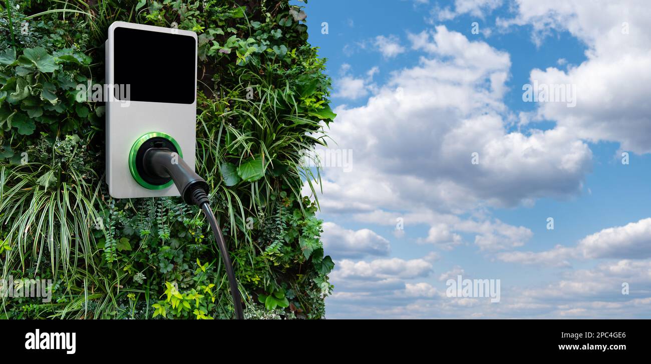 Stazione di ricarica per auto elettriche su una parete verde degli impianti Foto Stock