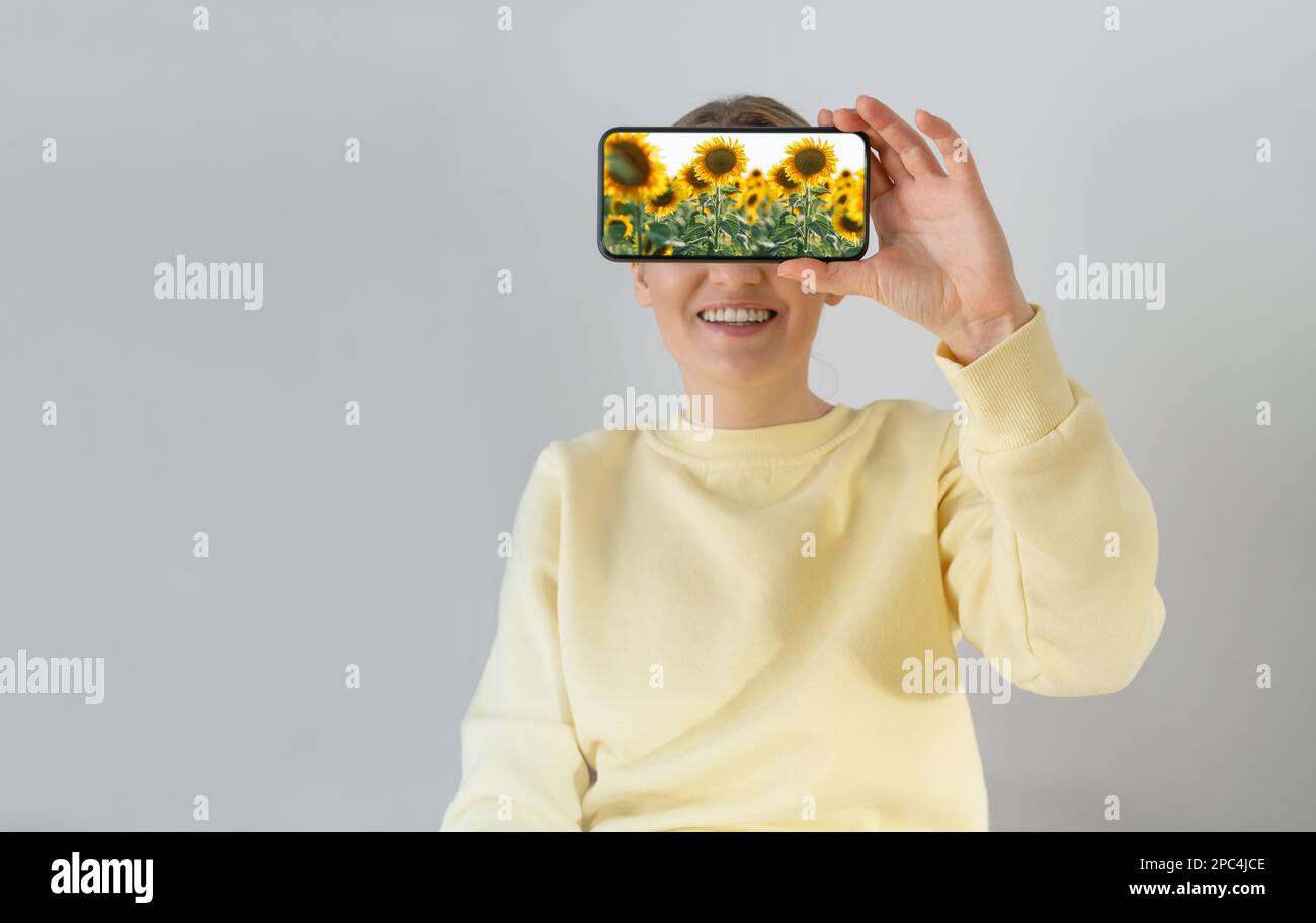 Una donna tiene in mano uno smartphone con i girasoli sullo schermo. Foto Stock