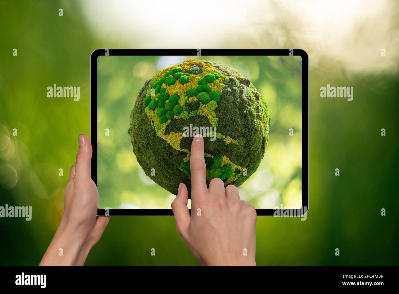 Mani che tengono il tablet digitale con il pianeta Terra verde su uno schermo Foto Stock