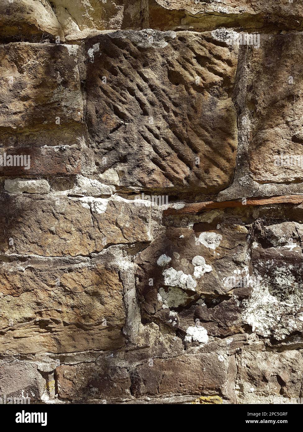 Particolare di un vecchio muro di pietra con ombre da un albero. Foto Stock