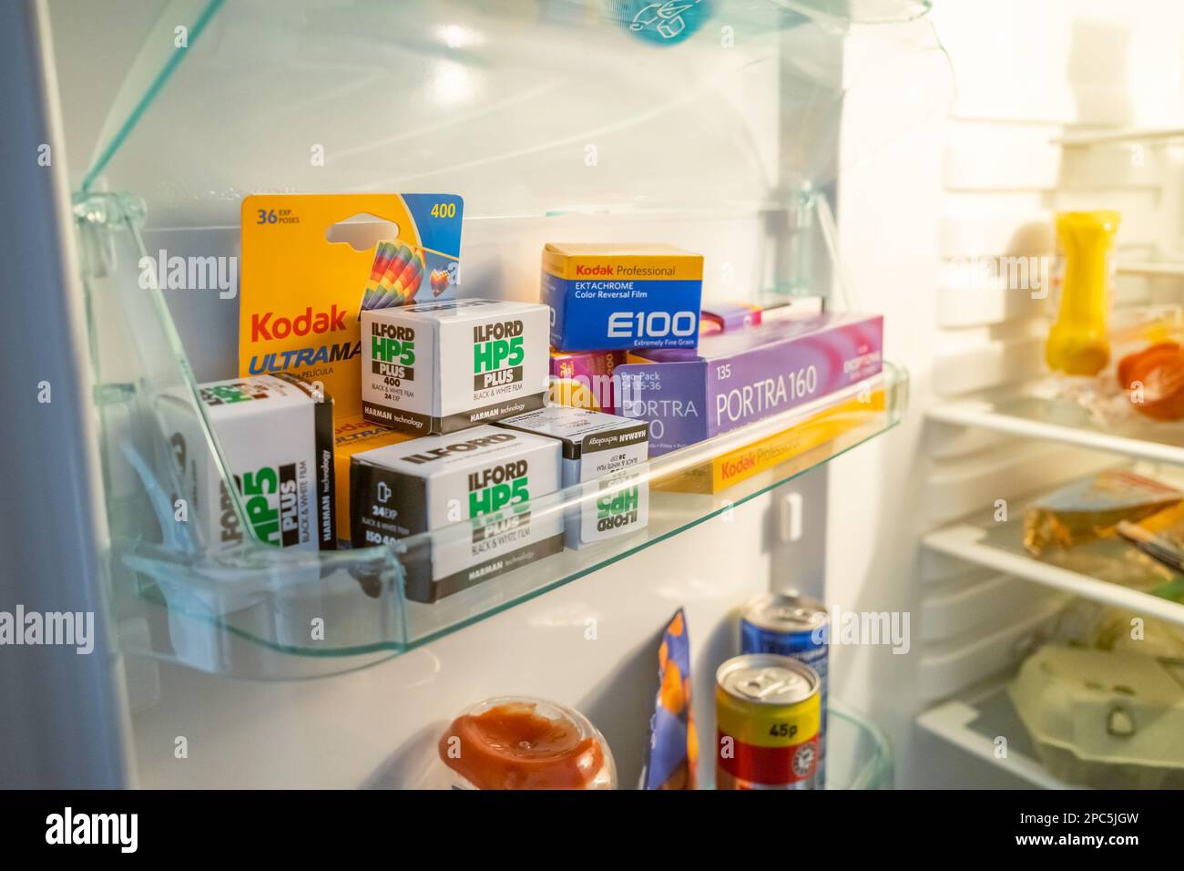 Aprire lo sportello del frigorifero che mostra uno scaffale pieno di pellicola da 35mm 135 mm, conservato a freddo per una maggiore durata. Mostrato nel contesto intorno ad altri prodotti alimentari Foto Stock