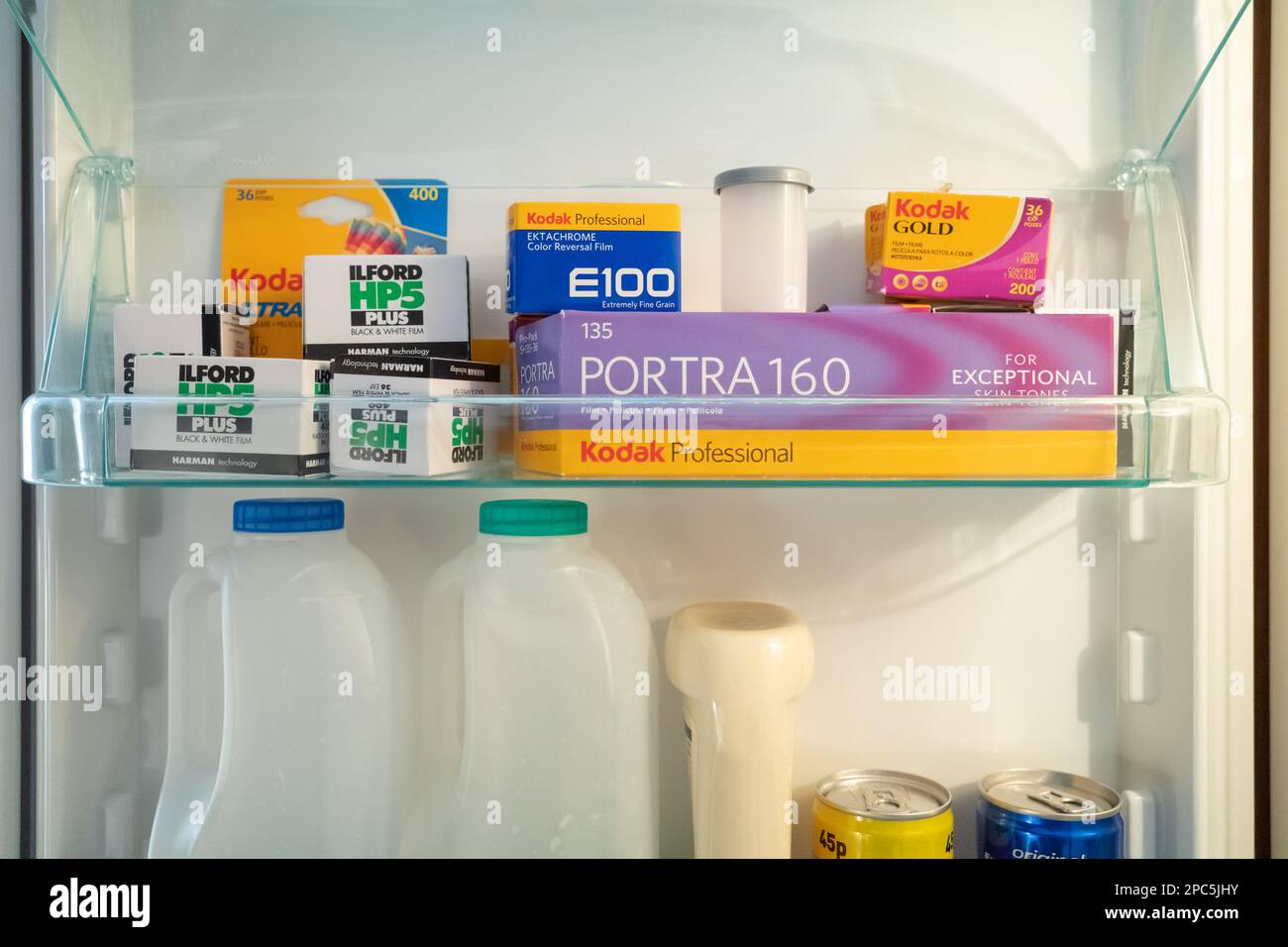 Aprire lo sportello del frigorifero che mostra uno scaffale pieno di pellicola da 35mm 135 mm, conservato a freddo per una maggiore durata. Mostrato nel contesto intorno ad altri prodotti alimentari Foto Stock