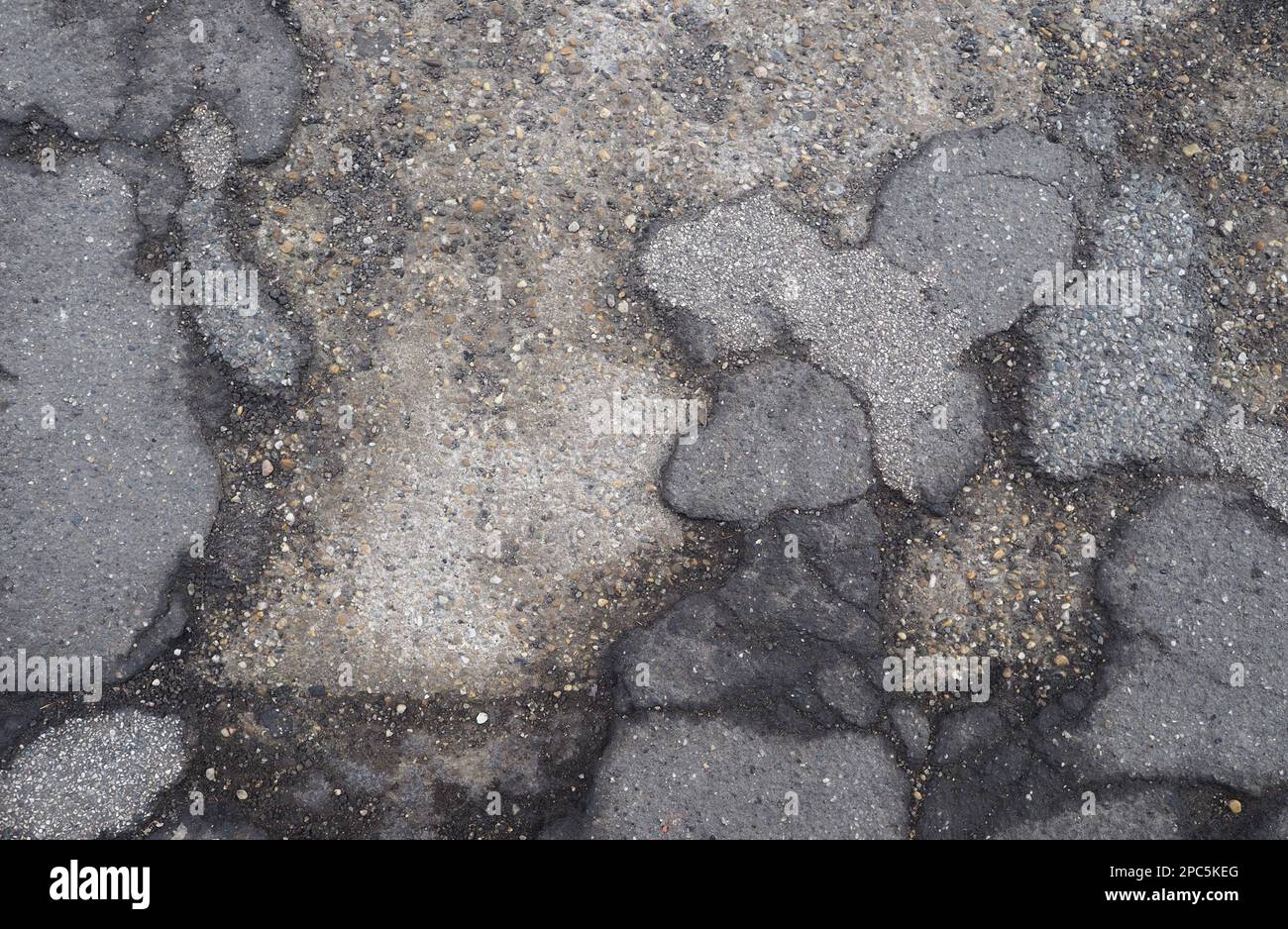 danni all'asfalto su pavimenti sgombrati che mostrano una soletta di cemento sottostante utile come sfondo Foto Stock