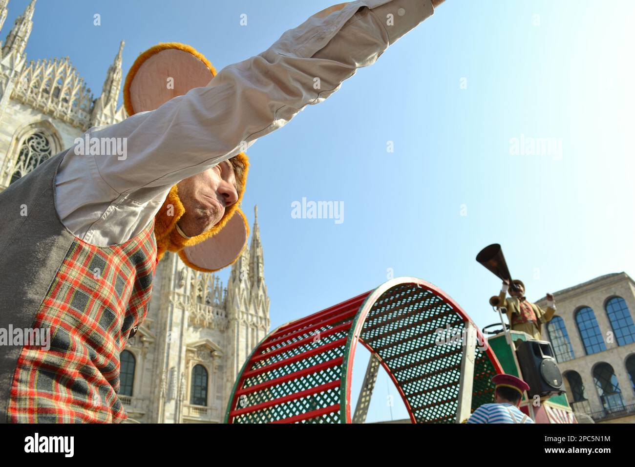 L'artista del circo vestito con una maschera di carnevale di criceto (mouse) in un cappello con due enormi griche di orecchie di micky-mouse sul suo volto e tira una mano diritta. Foto Stock