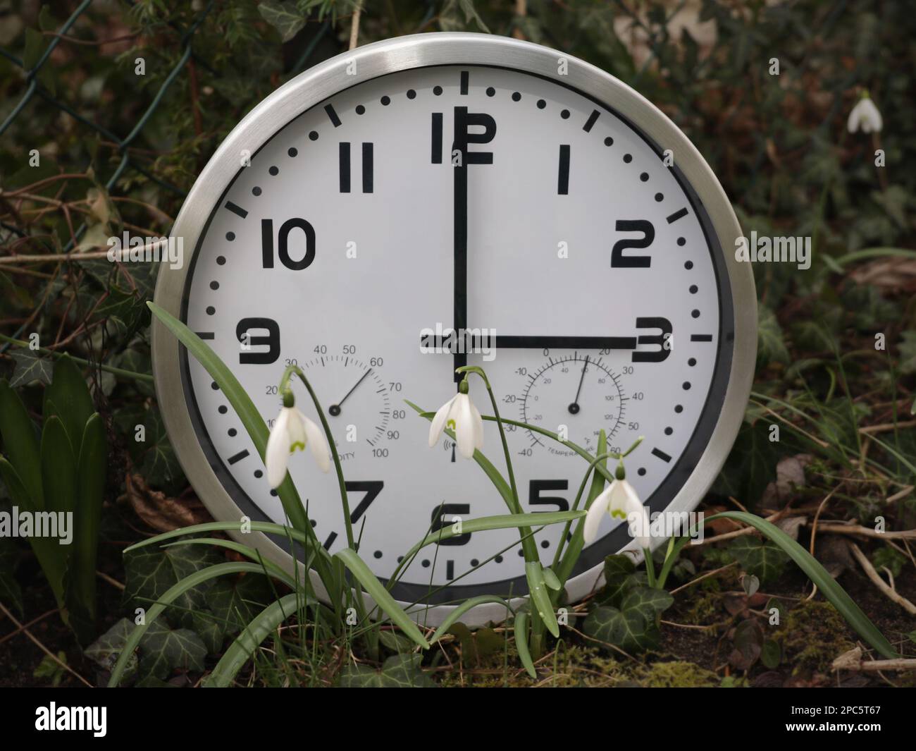 Un orologio che mostra tre ore si trova all'esterno in primavera. Un simbolo per il cambio di tempo. Ora legale. Spostare le mani in avanti. Foto Stock