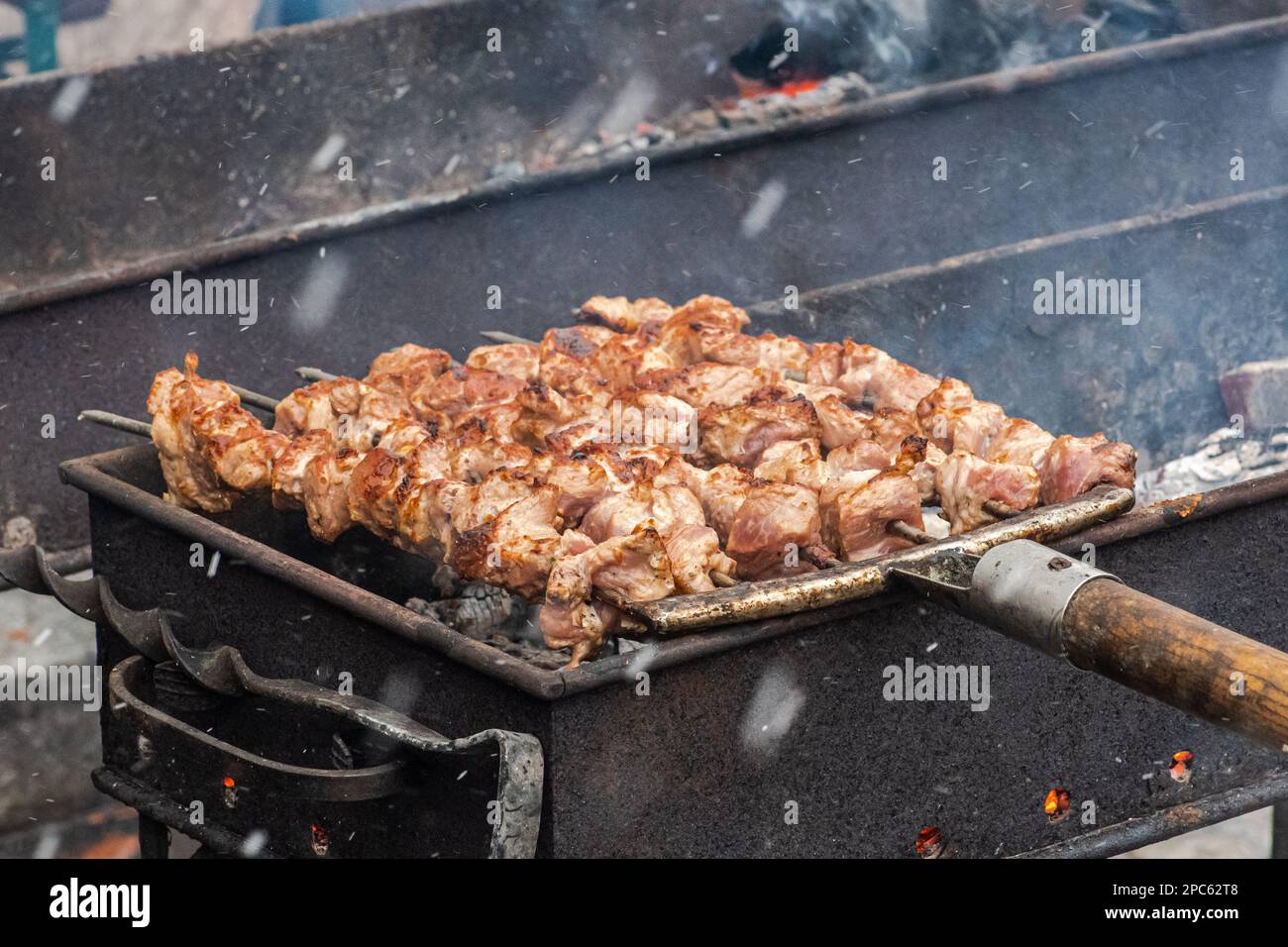 Spiedino di carne di maiale, grigliato o arrostito in un barbecue con forchette a fuoco aperto e fiamme, shashlik o shashlyk in un mercato di cibo di strada o un outd Foto Stock