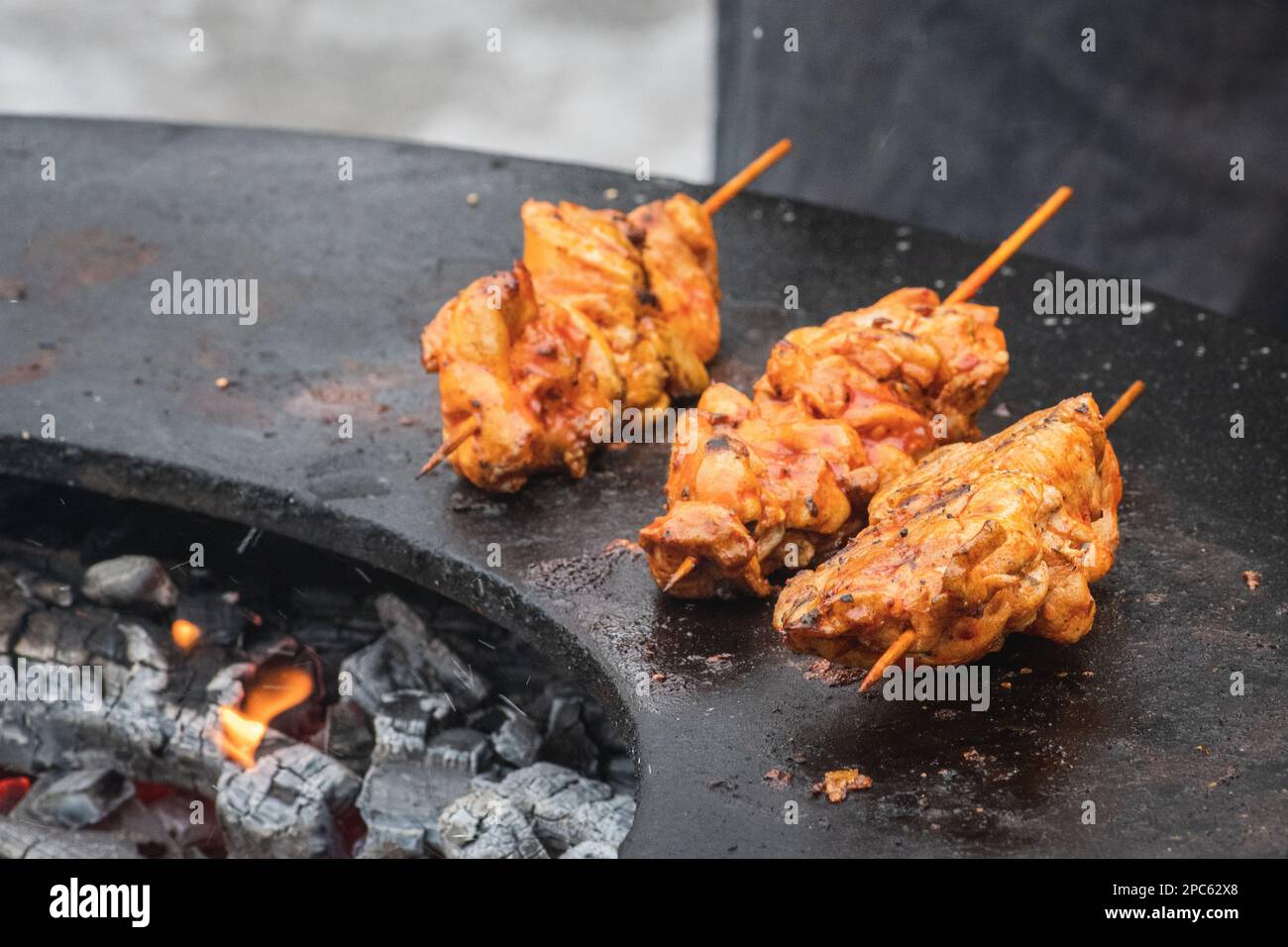 Preparare spiedini di carne di pollo, grigliati o arrostiti in un barbecue a fuoco aperto con fiamme, shashlik o shashlyk per un picnic all'aperto, primo piano Foto Stock