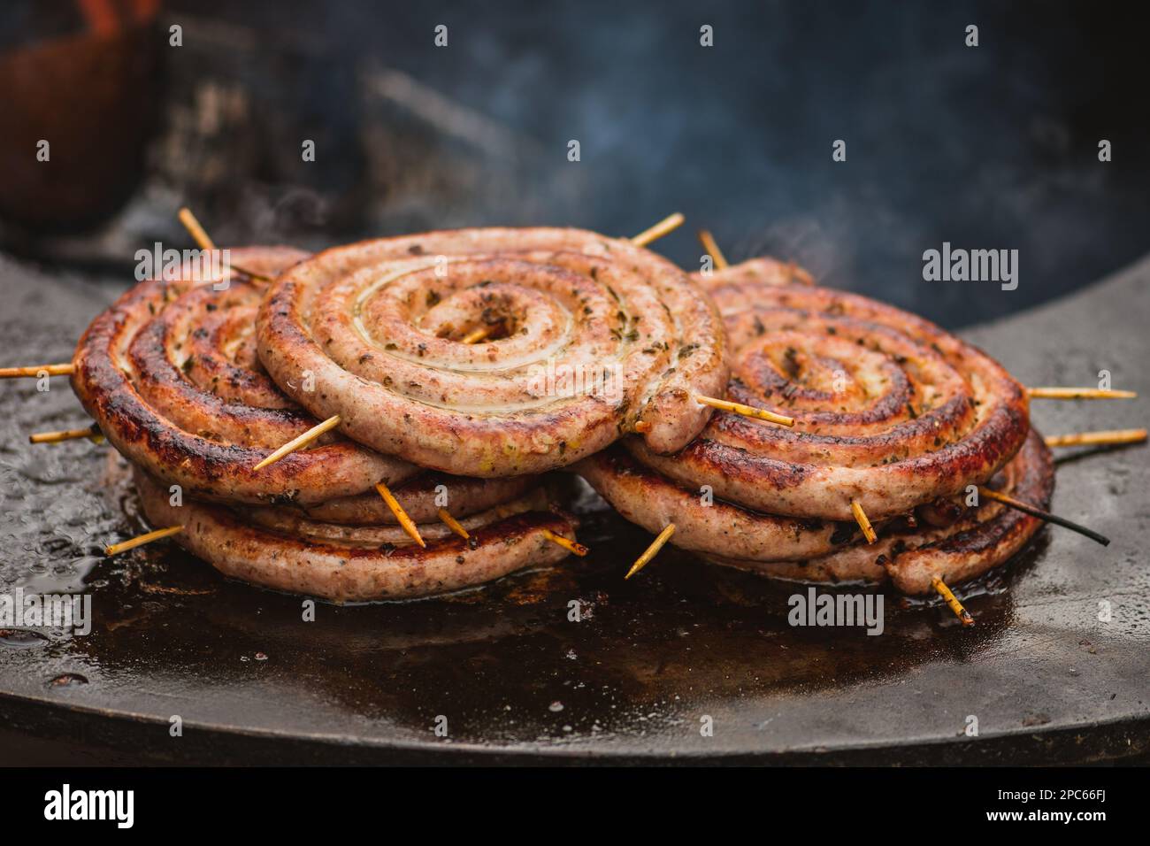 Salsicce arrotolate a spirale preparate con carne macinata alla griglia o arrostite in un barbecue sul fuoco aperto Foto Stock