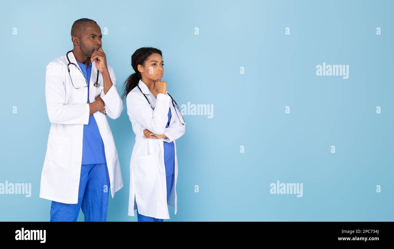 Pensivo sicuro medici afroamericani in uniforme bianca guardando lo spazio copia e pensare, panorama Foto Stock