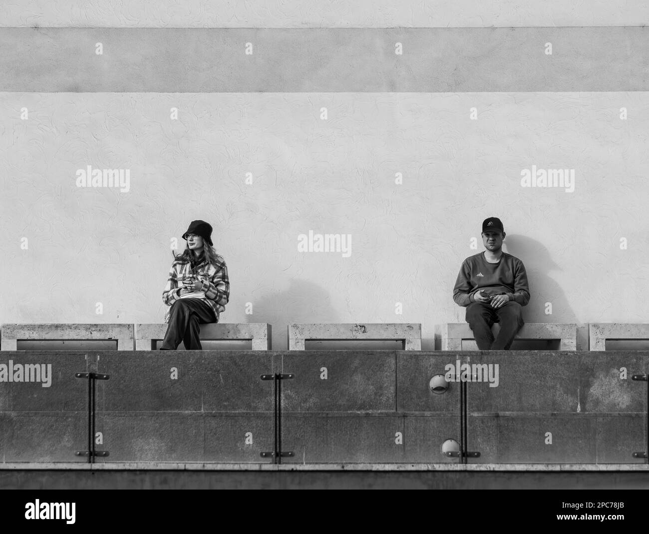 Bucarest, Romania - 02.25.2023: Fotografia di strada nel centro di Bucarest. Una giovane donna e un uomo seduto o in attesa su una panchina. Foto Stock
