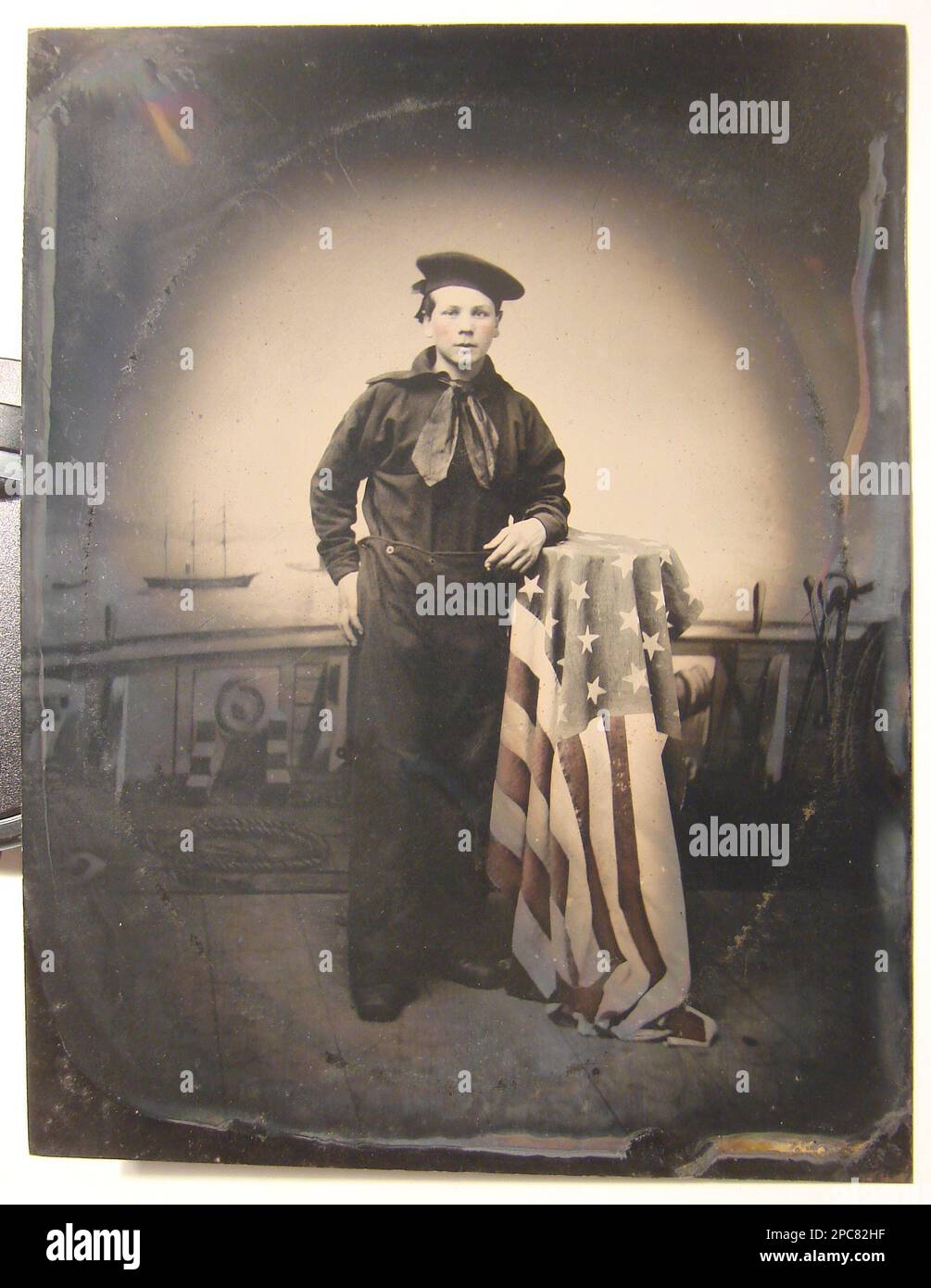 Giovane marinaio non identificato in uniforme Union con bandiera americana di fronte allo sfondo che mostra la scena navale. Stati Uniti, Marina, persone, 1860-1870, giovani, 1860-1870, marinai, 1870-1880, uniformi militari, 1860-1870, Flags, americano, 1870-1880, backdrops, 1860-1870, Stati Uniti, Storia, Guerra civile, 1861-1865, personale militare, Unione. Foto Stock