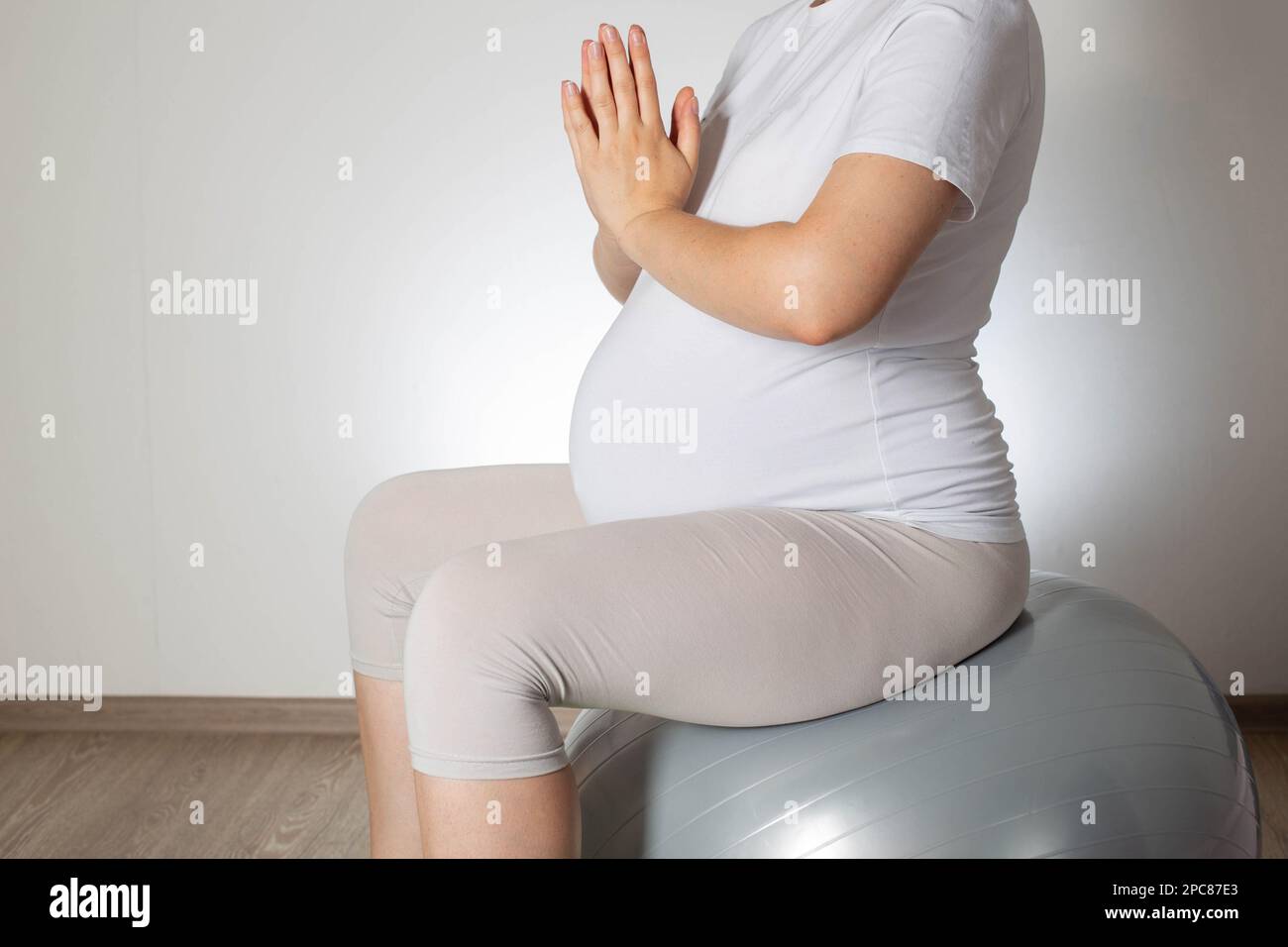 Relax e meditazione per una ragazza incinta su una palla da fitness su sfondo bianco. Salute delle donne, ginnastica Foto Stock