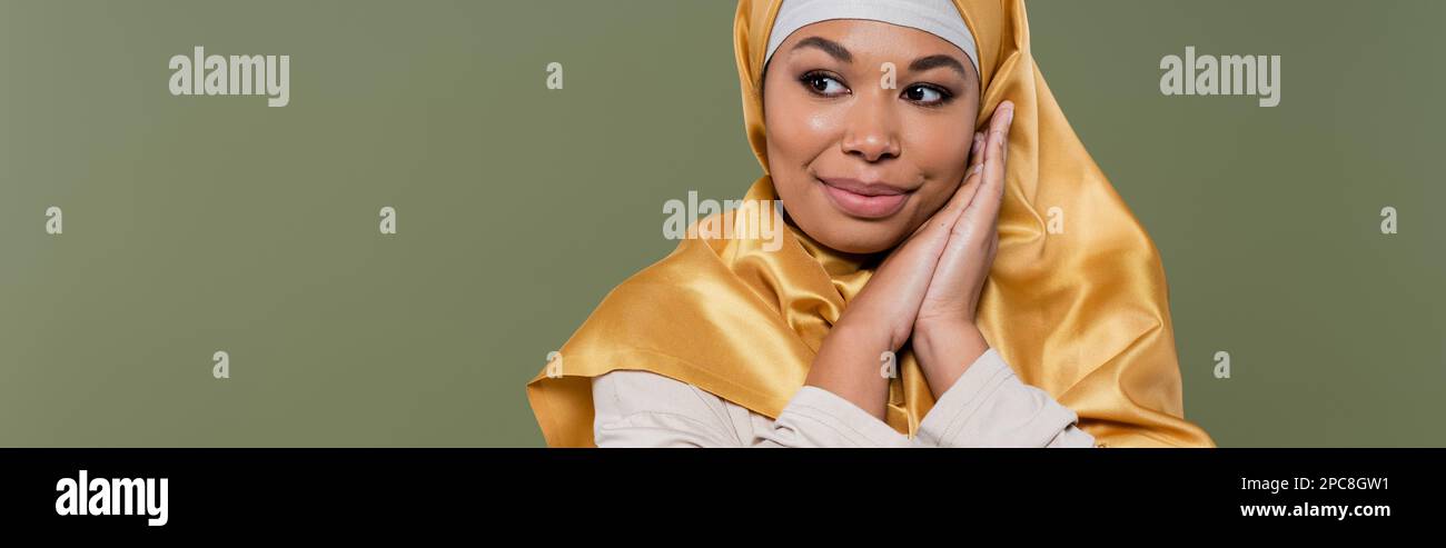 Bella donna multirazziale in hijab guardando lontano isolato su verde, banner, immagine stock Foto Stock