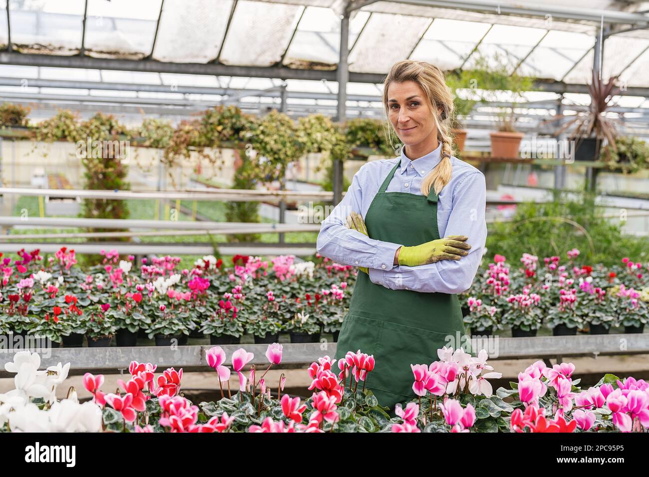 Ritratto di donna felice che lavora all'interno di serra o giardino centrale Foto Stock
