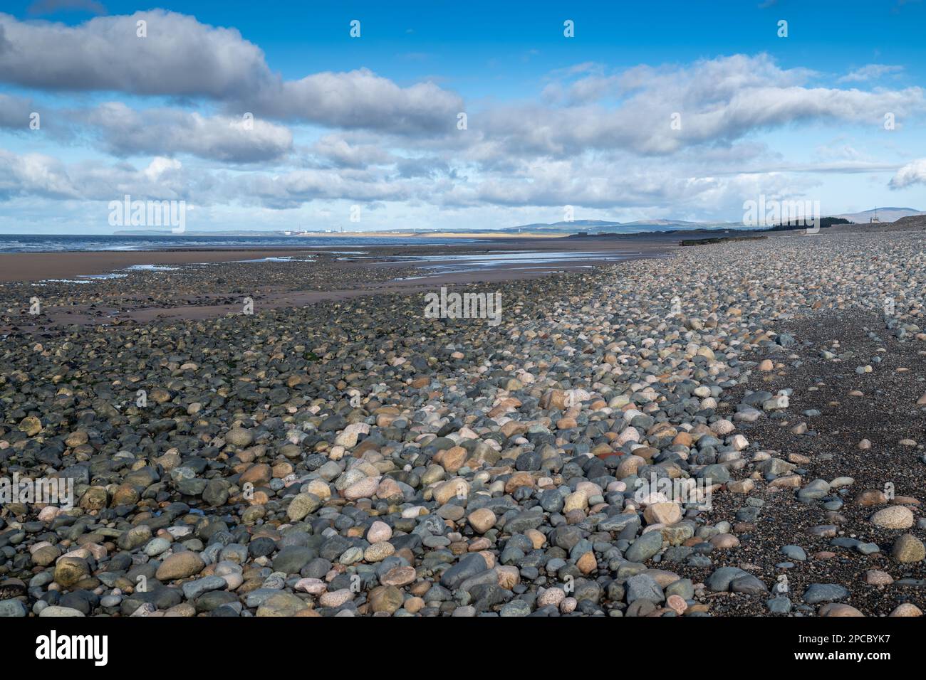 Onde che lambiscono una spiaggia di pietra al largo di Bootle in Cumbria, sulla costa del Mare d'Irlanda, guardando verso la centrale nucleare di Sellafield, Cumbria, Regno Unito. Foto Stock