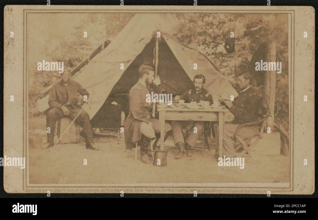 Tre soldati non identificati che mangiano al tavolo fuori dalla tenda mentre un soldato afroamericano siede accanto alla tenda con la spada sul ginocchio. Liljenquist Famiglia Collezione di fotografie della Guerra civile , pp/liljpaper. Stati Uniti, esercito, persone, 1860-1870, afroamericani, Servizio militare, 1860-1870, soldati, Unione, 1860-1870, Uniformi militari, Unione, 1860-1870, tende, 1860-1870, Mangiare & bere, 1860-1870, Daggers & spade, 1860-1870, Stati Uniti, Storia, Guerra civile, 1861-1865, personale militare, Unione, Stati Uniti, Storia, Guerra civile, 1861-1865, vita militare, Unione. Foto Stock
