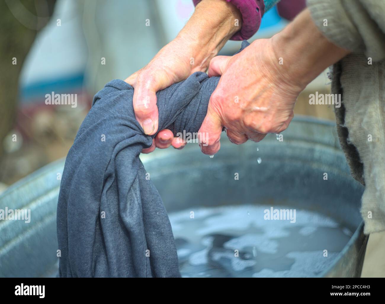 Donna che strizzava i vestiti dopo il lavaggio Foto Stock