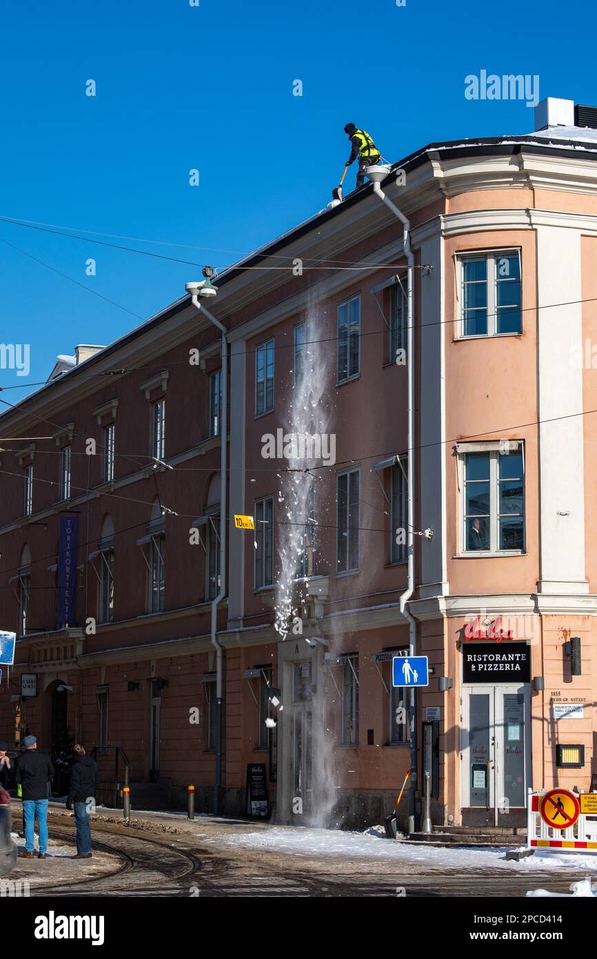 Rimozione della neve sul tetto in una giornata invernale soleggiata nel distretto di Kruunhaka di Helsinki, Finlandia Foto Stock