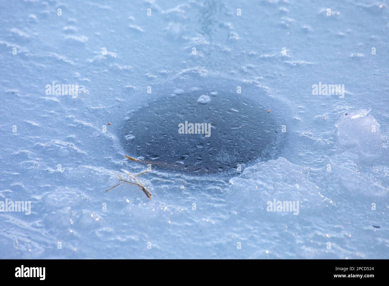 Foro per la pesca sul ghiaccio congelato Foto Stock