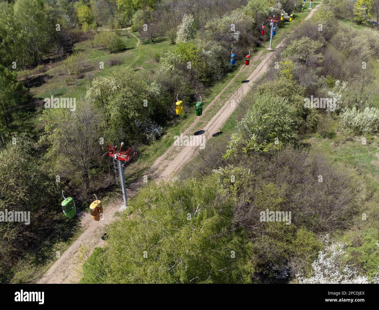 Volando sopra la funivia nel parco cittadino centrale di Kharkiv, guardate verso il basso. Alberi di primavera verde vista aerea dal drone Foto Stock