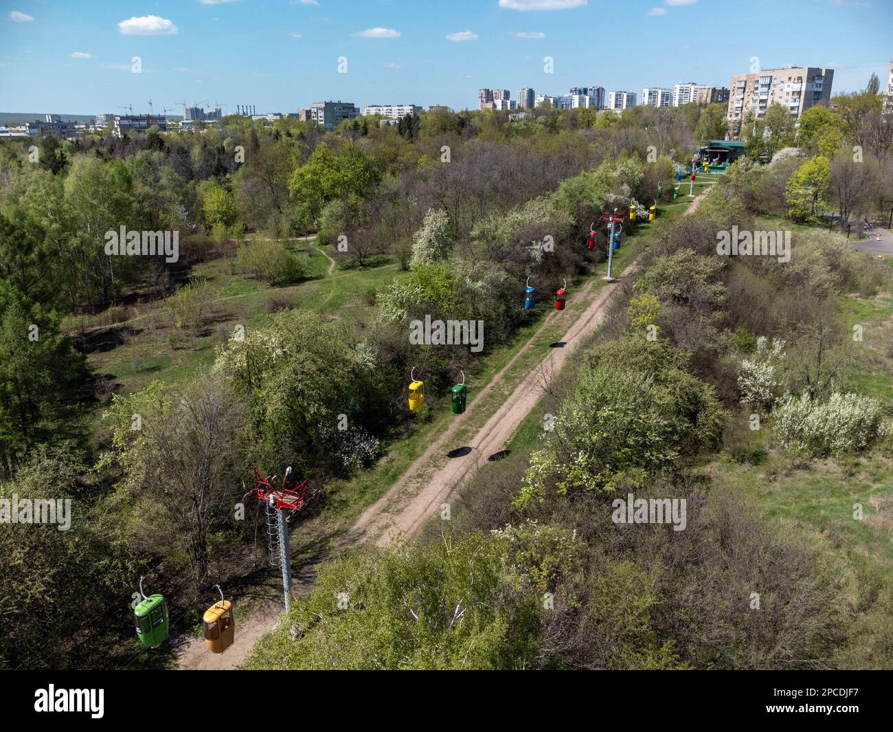 Sorvolando la funivia nel parco cittadino centrale di Kharkiv vicino al quartiere residenziale. Alberi di primavera verde vista aerea dal drone Foto Stock