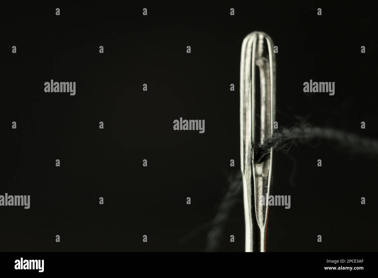 L'occhio di un ago con un filo vicino. Ago per cucire con filo penetrante. Utensile per cucire, ricamare Foto Stock