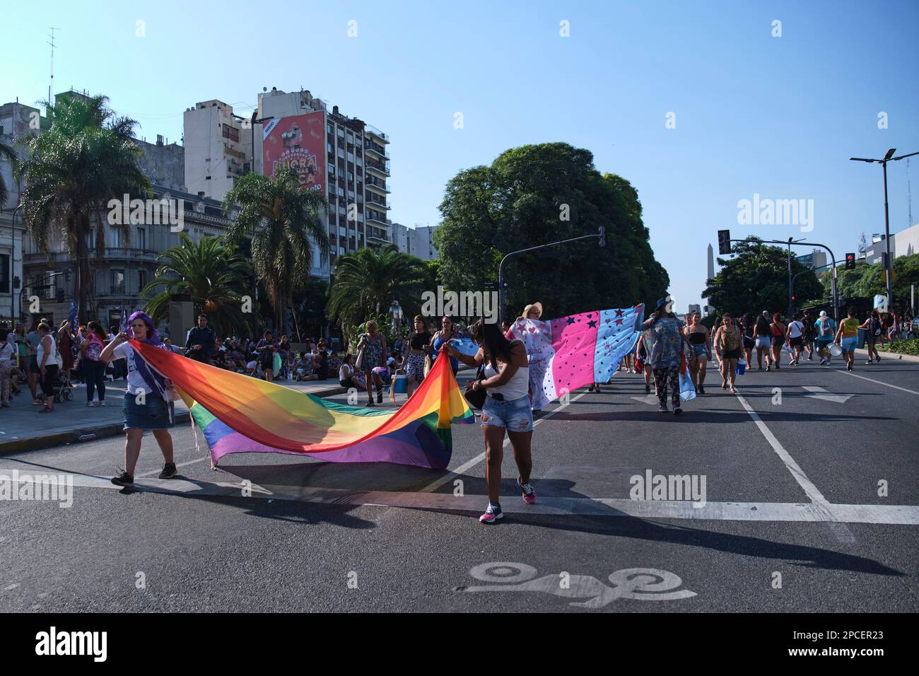 Buenos Aires, Argentina; 8 marzo 2023: Persone che marciano con una bandiera arcobaleno, un simbolo della comunità LGBTQ+, e una bandiera trans community durante l'i Foto Stock