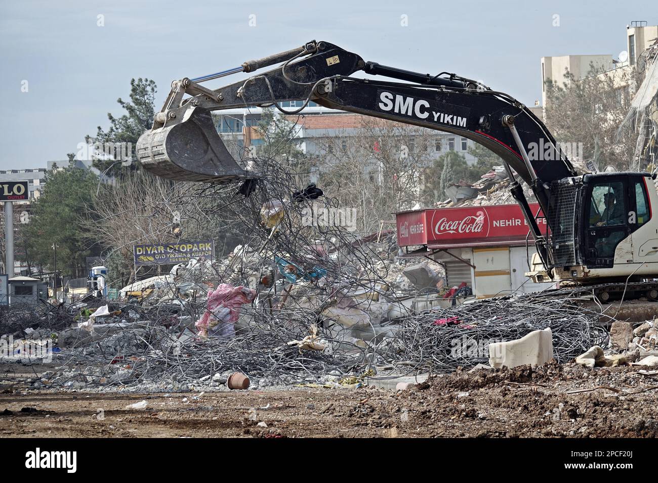 Un caricatore retroescavatore che elimina i detriti decomponendo i ferri da costruzione. Tonnellate di detriti pesanti del sito di Galeria, dove uno dei 4 blocchi è crollato e ha ucciso 89 persone nella città di Diyarbakir durante i gravi terremoti che si sono verificati il 6 febbraio in Turchia, è in corso di pulizia. Inizialmente, il ferro e altri residui metallici vengono separati dal calcestruzzo e inviati per il riciclaggio. Il sito si compone di 12 piani e 4 blocchi. Anche i 4 piani inferiori del centro commerciale e i due e terzi blocchi del sito gravemente danneggiato sono stati demoliti sotto controllo, l'ultimo blocco sarà demolito anche soo Foto Stock