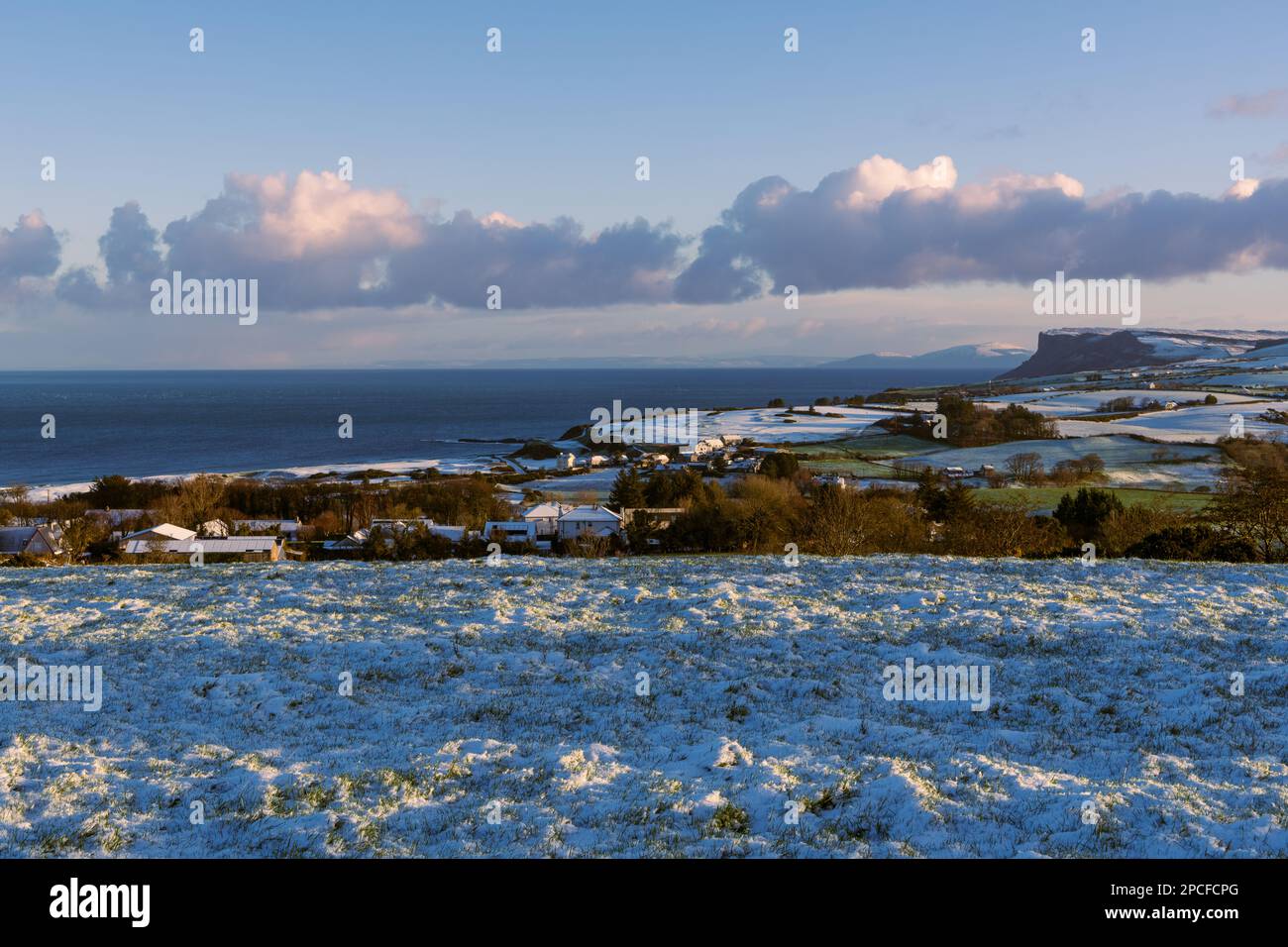 Erba innevata e campi alla luce della mattina presto lungo la costa di Antrim a Ballycastle, Irlanda del Nord Foto Stock