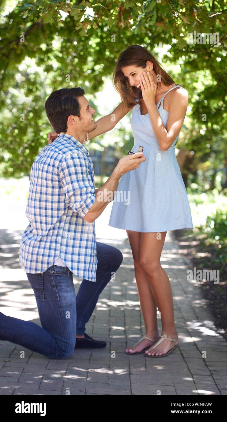 Vuoi... Un giovane che si inginocchia nel parco e chiede alla sua ragazza di sposarlo. Foto Stock